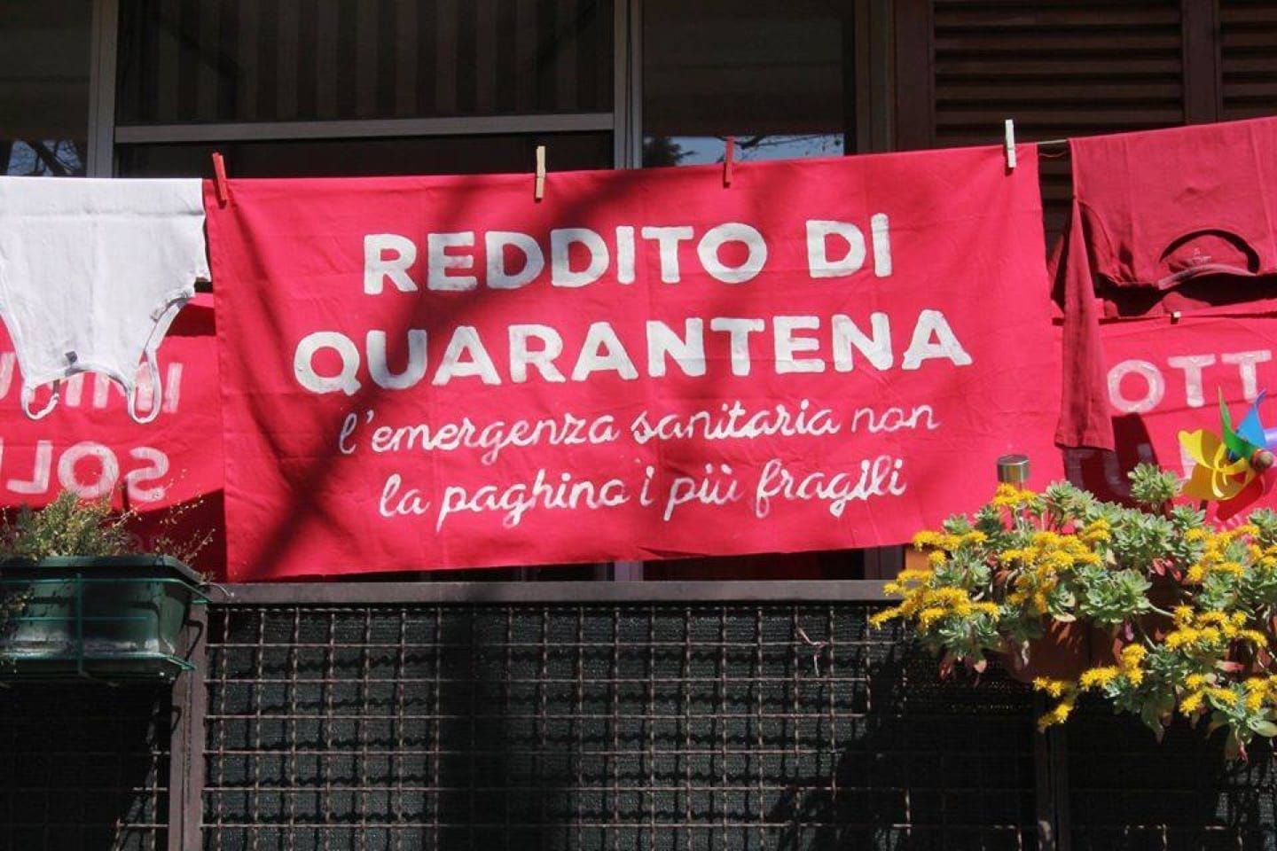 uno striscione rosso con scritto Reddito di quarantena